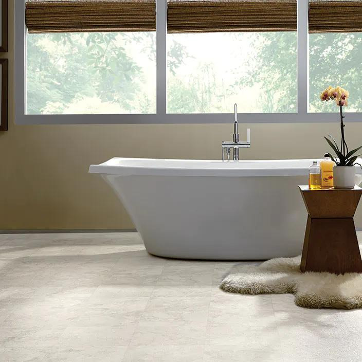 White bathtub in front of a window on vinyl floor